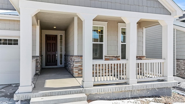 snow covered property entrance with a garage and a porch