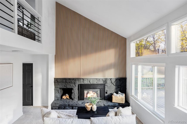 carpeted living area featuring a fireplace, high vaulted ceiling, and baseboards