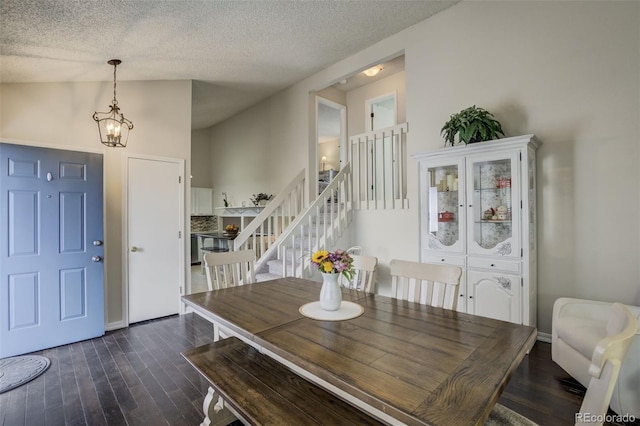 dining area with a notable chandelier, dark wood-style flooring, a textured ceiling, vaulted ceiling, and stairs