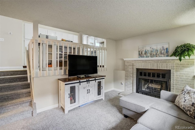 carpeted living area with stairs, a brick fireplace, a textured ceiling, and baseboards