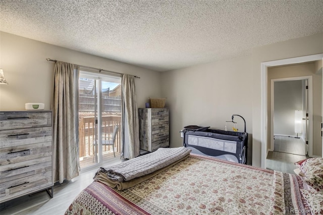 bedroom with a textured ceiling, access to outside, and light wood finished floors