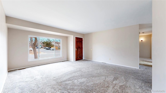 spare room featuring carpet flooring and baseboards