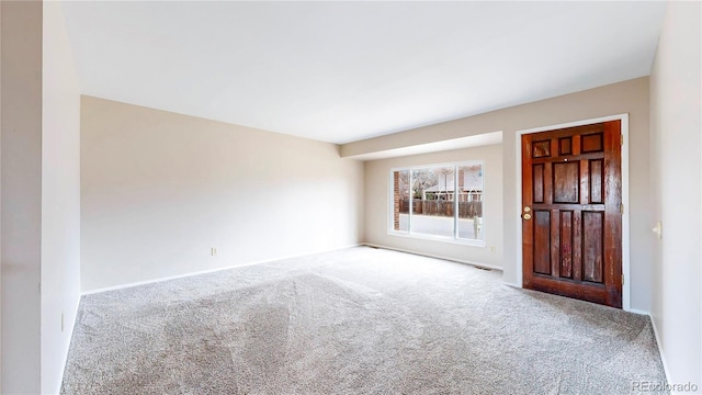 empty room featuring carpet floors, visible vents, and baseboards