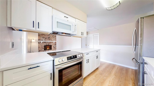 kitchen with light countertops, appliances with stainless steel finishes, light wood-type flooring, and white cabinets