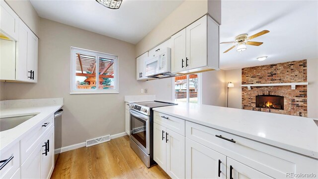 kitchen featuring light wood-style flooring, stainless steel appliances, visible vents, baseboards, and light countertops