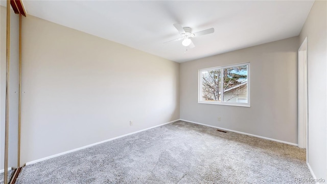 carpeted spare room with ceiling fan and baseboards