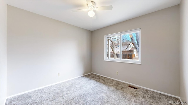 spare room with ceiling fan, carpet floors, visible vents, and baseboards