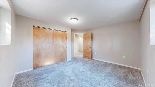 unfurnished bedroom featuring carpet floors, visible vents, baseboards, and a closet