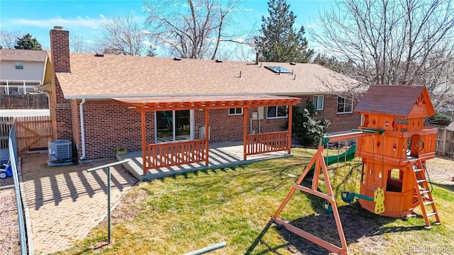 back of house featuring a playground, brick siding, fence, roof with shingles, and a chimney