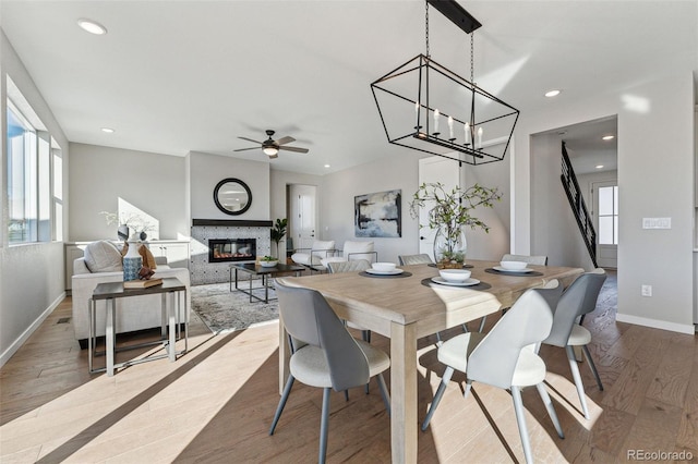 dining space with ceiling fan with notable chandelier and light wood-type flooring