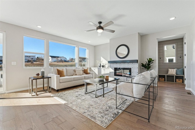 living room featuring ceiling fan, a fireplace, and wood-type flooring