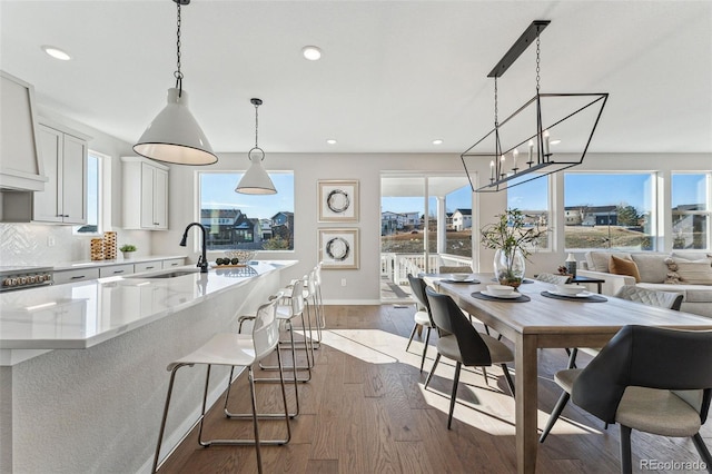 kitchen with white cabinetry, sink, dark wood-type flooring, pendant lighting, and decorative backsplash