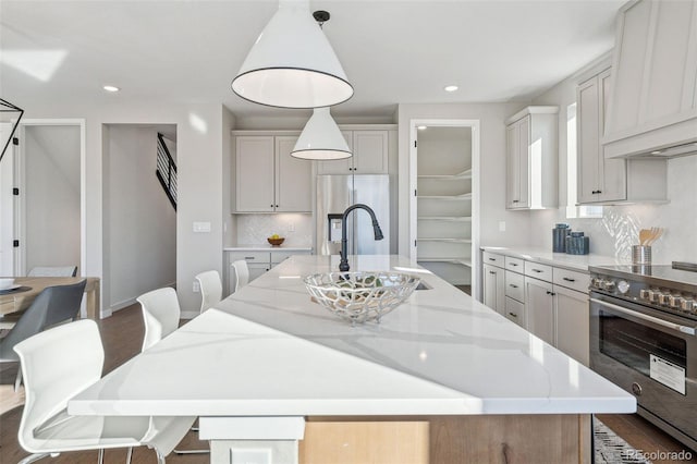 kitchen with a spacious island, premium range hood, hanging light fixtures, and appliances with stainless steel finishes