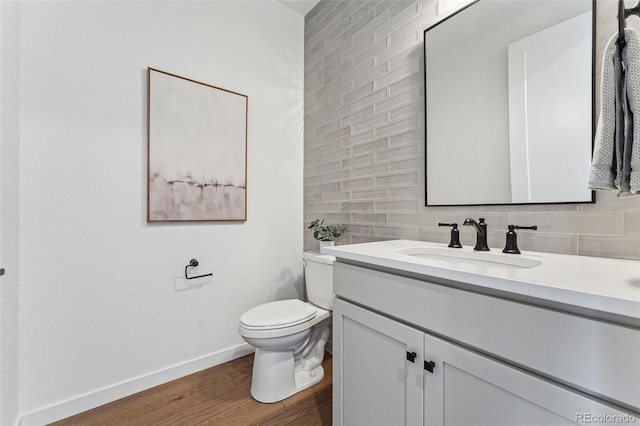 bathroom featuring decorative backsplash, hardwood / wood-style floors, vanity, and toilet