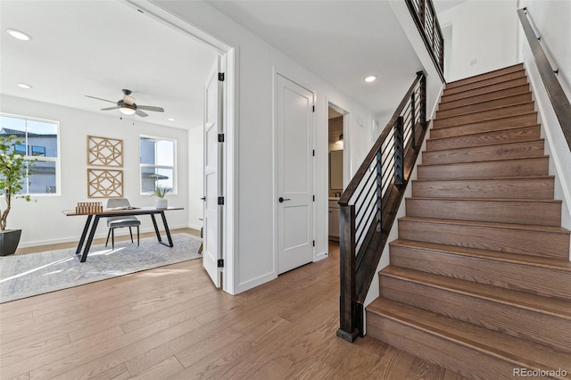 stairway with ceiling fan and wood-type flooring