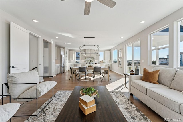 living room with wood-type flooring and ceiling fan with notable chandelier