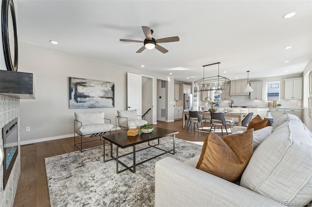 living room featuring ceiling fan with notable chandelier and dark hardwood / wood-style flooring