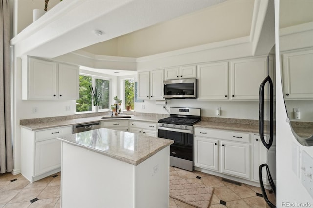 4520 Maroon Cir, Broomfield, CO 80023 - kitchen with appliances with stainless steel finishes, white cabinets, a center island, and light tile patterned flooring