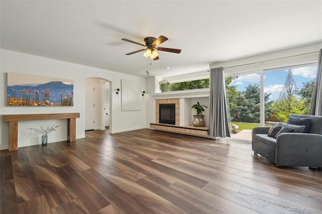 4520 Maroon Cir, Broomfield, CO 80023 - living area featuring a ceiling fan, arched walkways, wood finished floors, a tiled fireplace, and baseboards