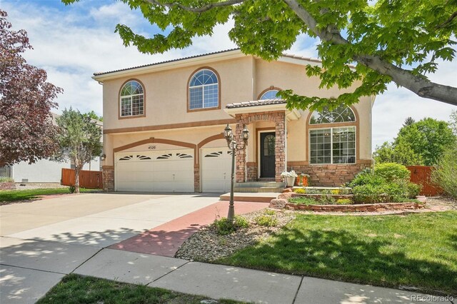 4520 Maroon Cir, Broomfield, CO 80023 - mediterranean / spanish home with an attached garage, driveway, stone siding, fence, and stucco siding