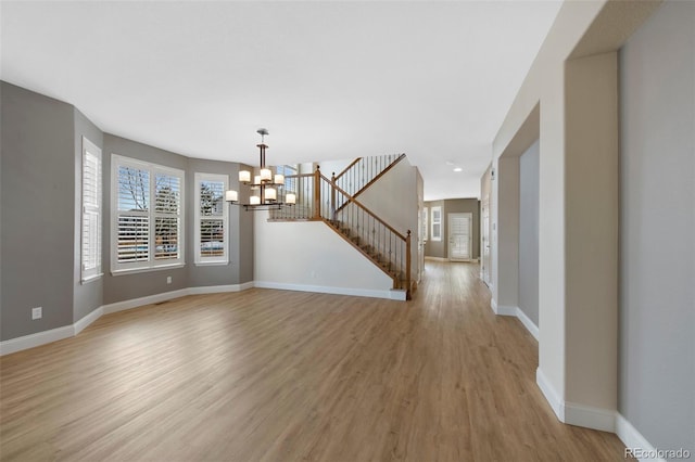 interior space with light wood-style flooring, stairs, baseboards, and a notable chandelier