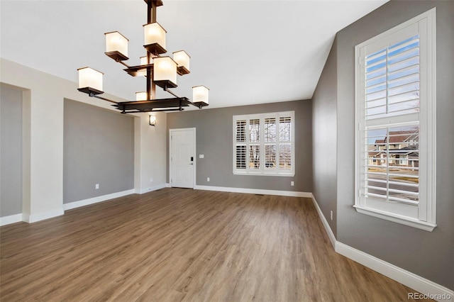 spare room with baseboards, wood finished floors, and a healthy amount of sunlight