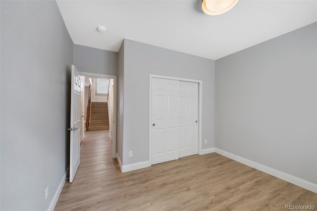 unfurnished bedroom with light wood-type flooring, baseboards, and a closet