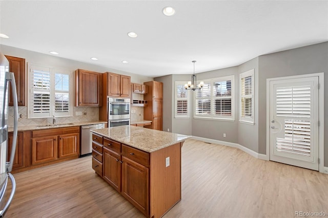 kitchen with stainless steel appliances, light wood-type flooring, and brown cabinets