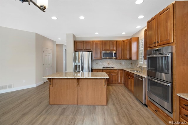 kitchen with tasteful backsplash, visible vents, appliances with stainless steel finishes, a sink, and a kitchen island