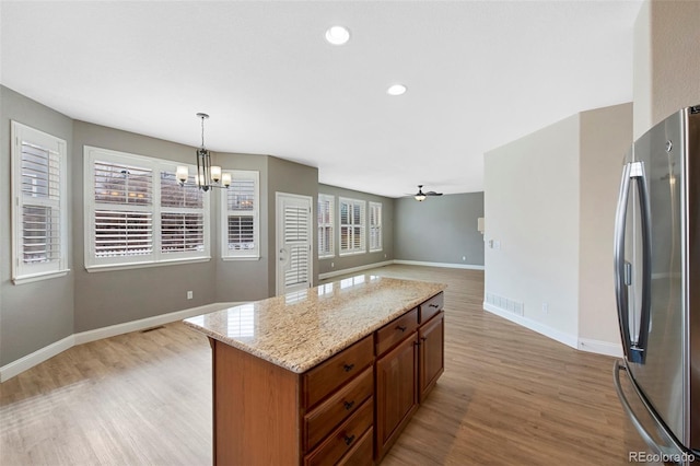 kitchen featuring pendant lighting, light wood finished floors, freestanding refrigerator, open floor plan, and baseboards