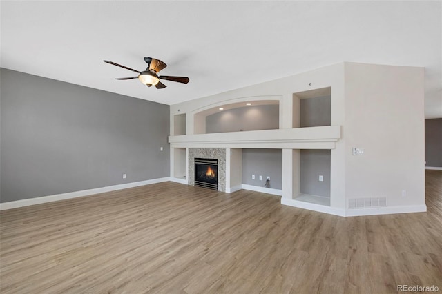 unfurnished living room with a ceiling fan, light wood-type flooring, visible vents, and a fireplace