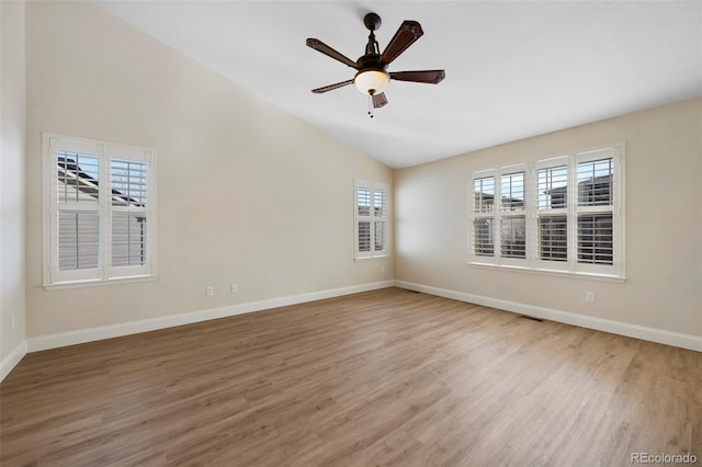 empty room featuring light wood-style floors, baseboards, vaulted ceiling, and a ceiling fan