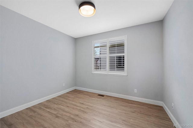 spare room with light wood-style floors, visible vents, and baseboards