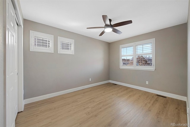 empty room with light wood-type flooring, visible vents, ceiling fan, and baseboards