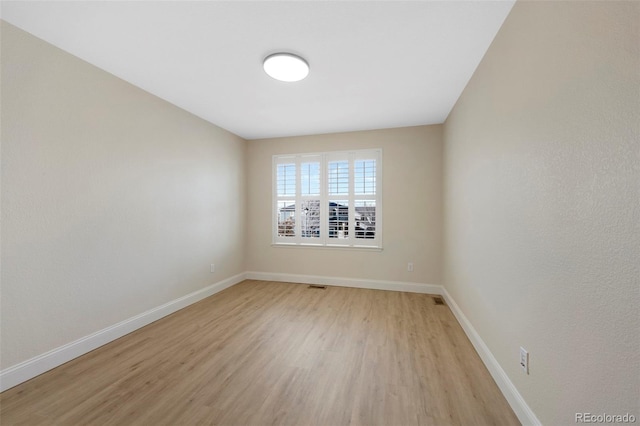 unfurnished room featuring light wood-style flooring, visible vents, and baseboards