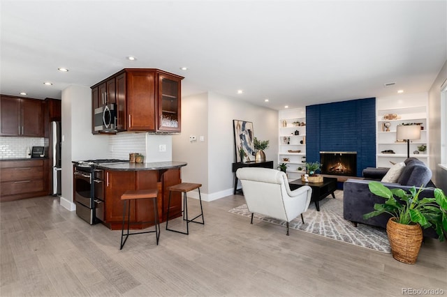 5743 Field St, Arvada, CO 80002 - kitchen featuring gas stove, freestanding refrigerator, stainless steel microwave, light wood-type flooring, and a breakfast bar