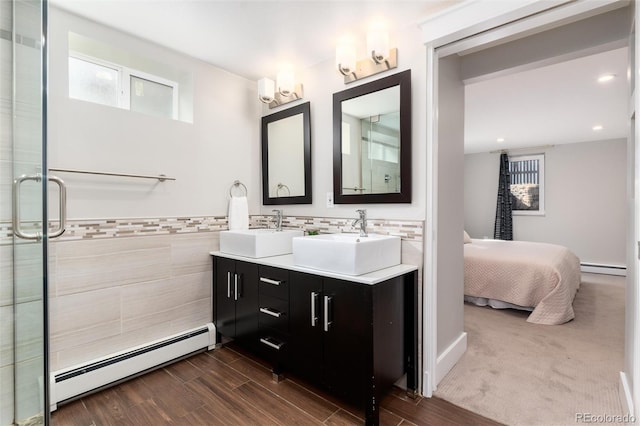 5743 Field St, Arvada, CO 80002 - bathroom with a baseboard heating unit, double vanity, a shower stall, wood finished floors, and recessed lighting