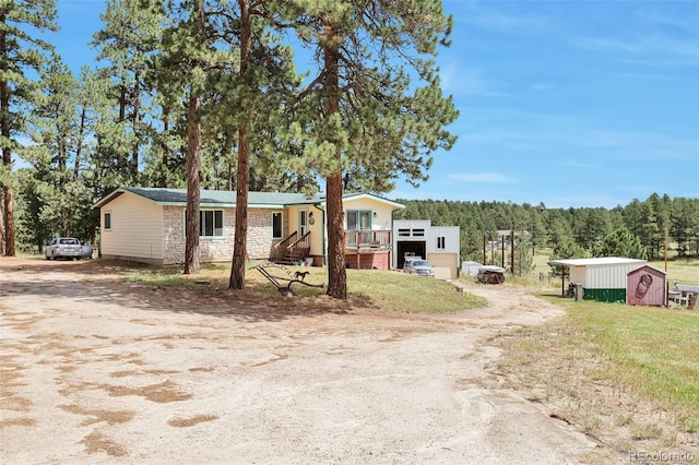 10771 Winding Meadow Dr, Kiowa, CO 80117 - manufactured / mobile home with dirt driveway, stone siding, and an outdoor structure