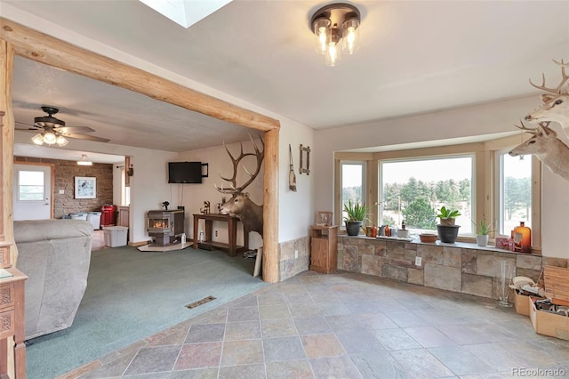 10771 Winding Meadow Dr, Kiowa, CO 80117 - living area featuring a skylight, visible vents, a ceiling fan, light colored carpet, and a wood stove