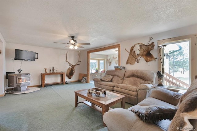 10771 Winding Meadow Dr, Kiowa, CO 80117 - carpeted living room featuring a textured ceiling, ceiling fan, a wood stove, and baseboards