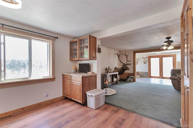 10771 Winding Meadow Dr, Kiowa, CO 80117 - kitchen featuring light countertops, glass insert cabinets, brown cabinetry, a textured ceiling, and light wood-type flooring