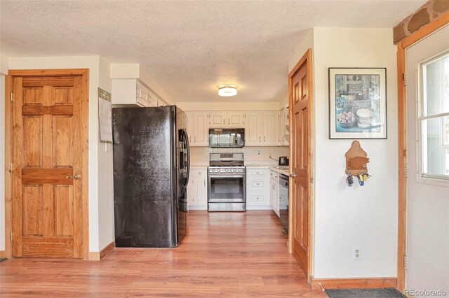 10771 Winding Meadow Dr, Kiowa, CO 80117 - kitchen featuring a textured ceiling, white cabinets, light countertops, light wood-type flooring, and black appliances