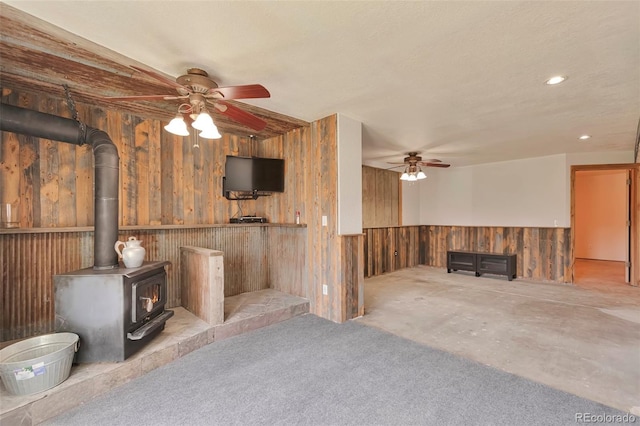 10771 Winding Meadow Dr, Kiowa, CO 80117 - unfurnished living room with wooden walls, wainscoting, ceiling fan, a wood stove, and recessed lighting