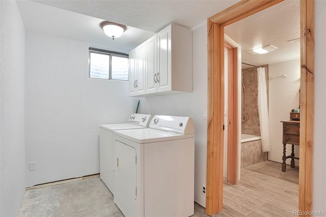 10771 Winding Meadow Dr, Kiowa, CO 80117 - clothes washing area with cabinet space, a textured wall, washing machine and clothes dryer, a textured ceiling, and light wood-type flooring