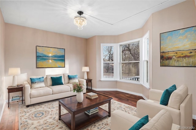 living room featuring a chandelier, baseboards, and wood finished floors