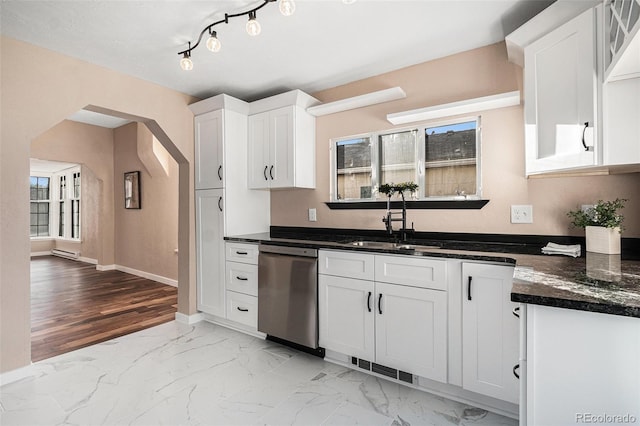 kitchen featuring arched walkways, dishwasher, marble finish floor, white cabinetry, and a sink