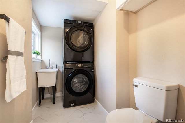 laundry room with laundry area, a sink, baseboards, stacked washer / drying machine, and marble finish floor