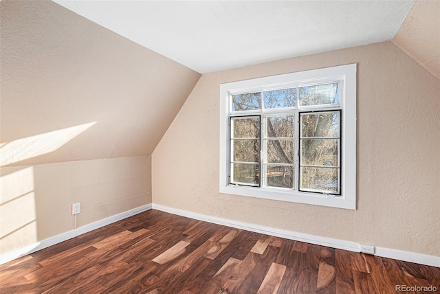 additional living space with a textured wall, vaulted ceiling, baseboards, and wood finished floors