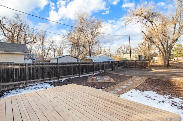 snow covered deck with a fenced backyard