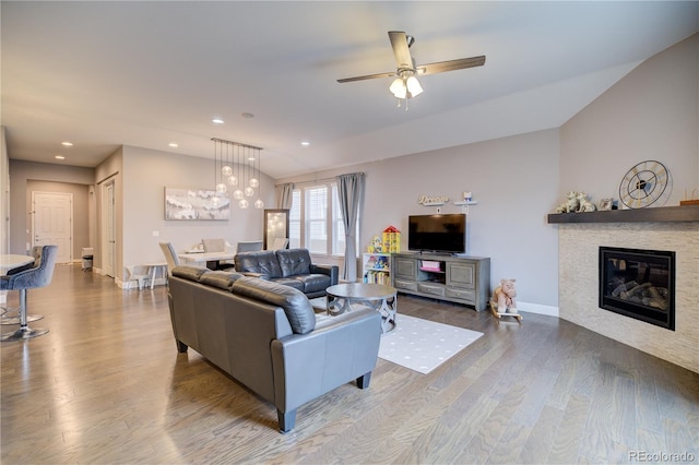 living area with lofted ceiling, recessed lighting, wood finished floors, baseboards, and a glass covered fireplace